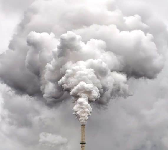 Smoke from factory pipe against dark overcast sky